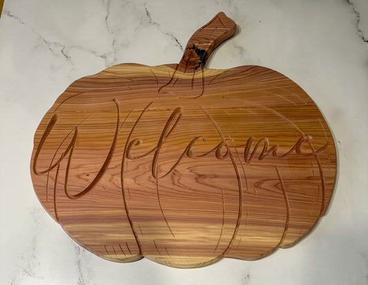 Wooden pumpkin-shaped door hanger with 'Welcome' engraving on a marble surface